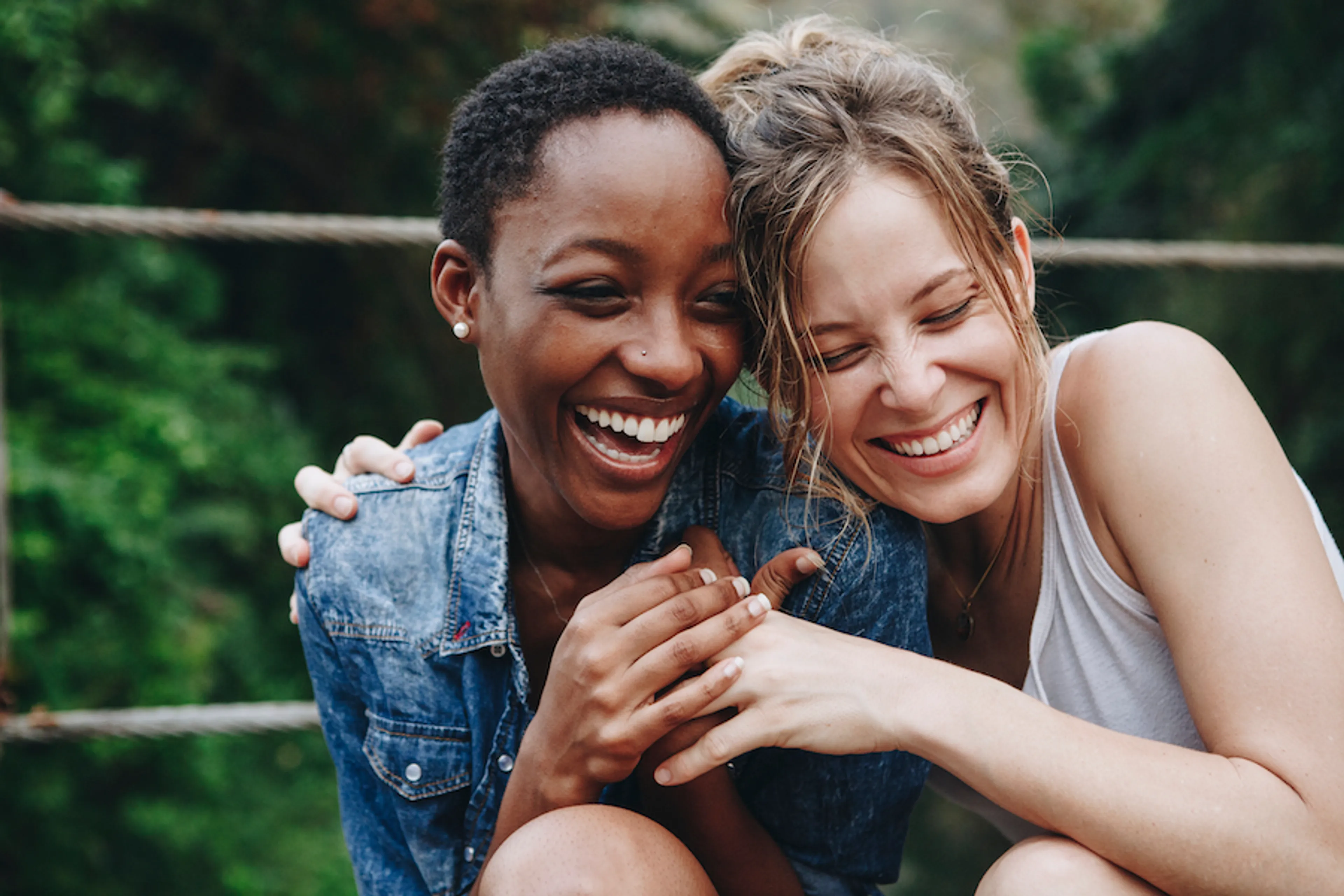 Twee vrouwen zijn vriendinnen en lachen samen terwijl ze elkaar omarmen.